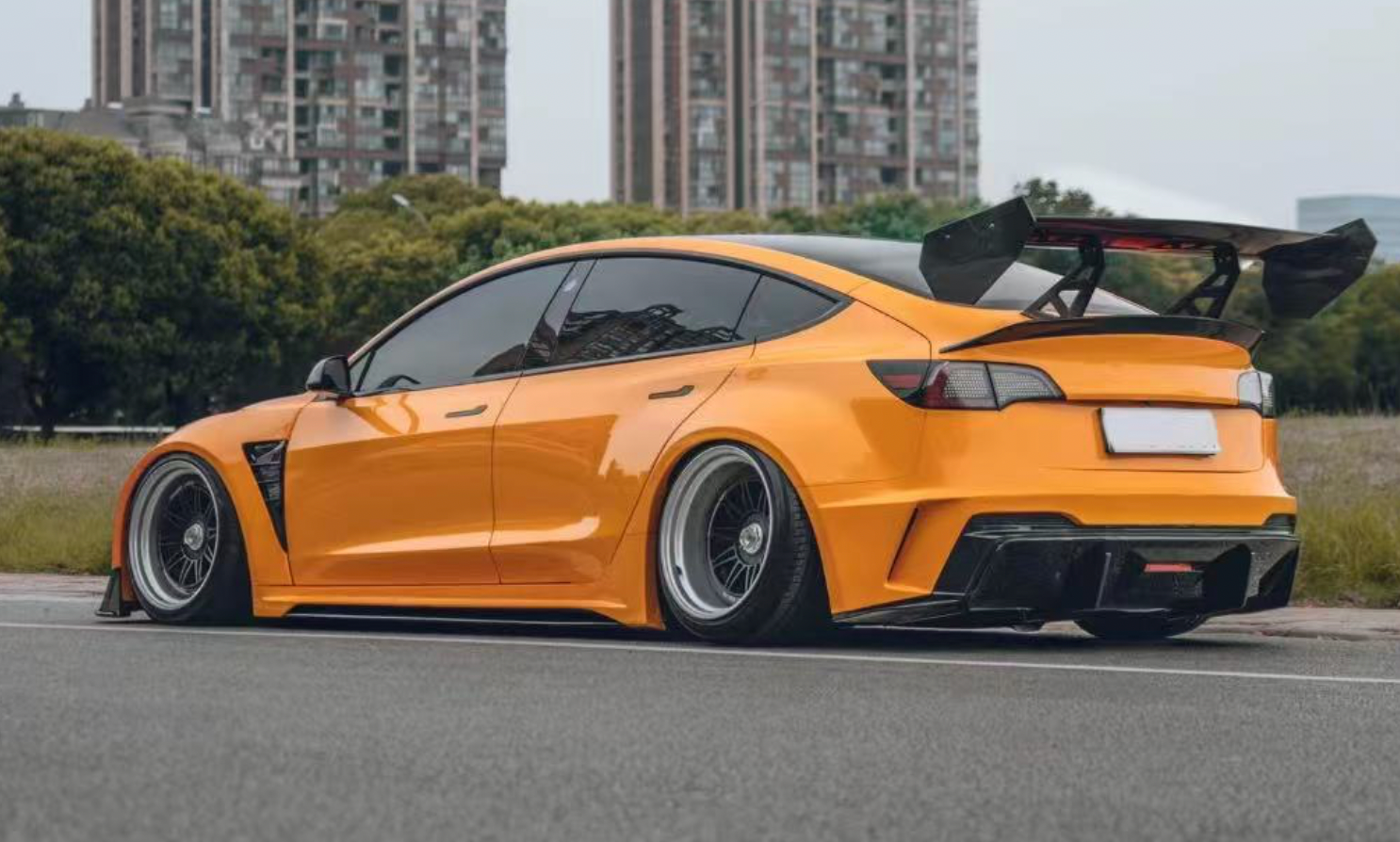 Seitlich hinten einen Orangenen Tesla Model 3